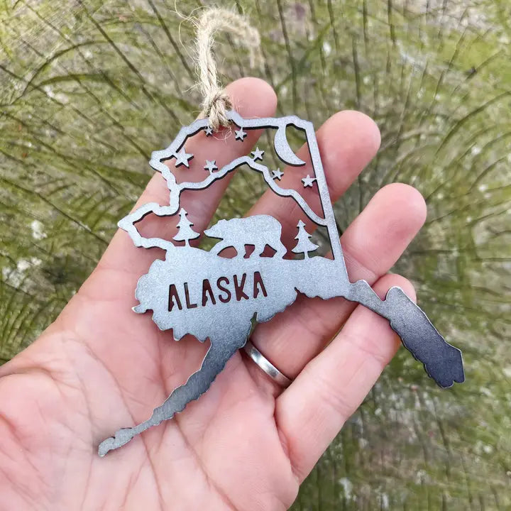 Metal ornament shaped like Alaska with 'Alaska' text and a bear and stars