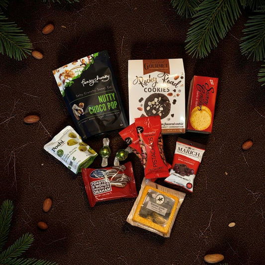 Assorted snack packages on a textured surface with greenery