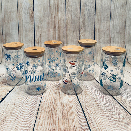 Glass tumblers with various winter-themed graphics, including snowflakes and Christmas trees, each with a bamboo lid.