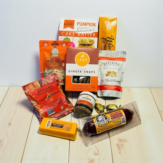 Assorted food products including snacks and condiments on a wooden surface with a white background