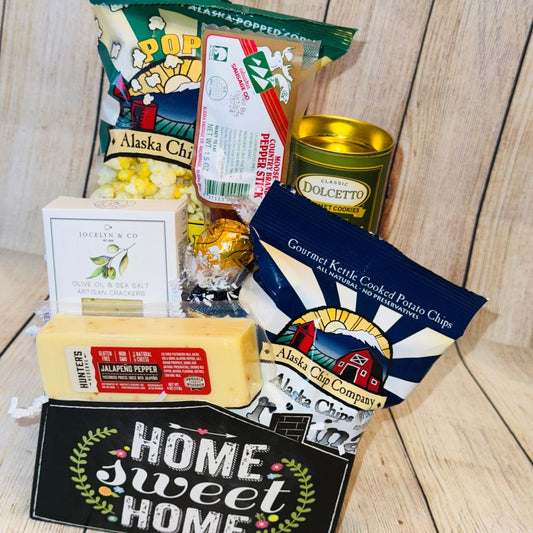 A gift basket with the text 'Home Sweet Home' containing various snack items including crackers, cheese, rolled wafers, meat stick, caramel popcorn, potato chips, and chocolate truffles.