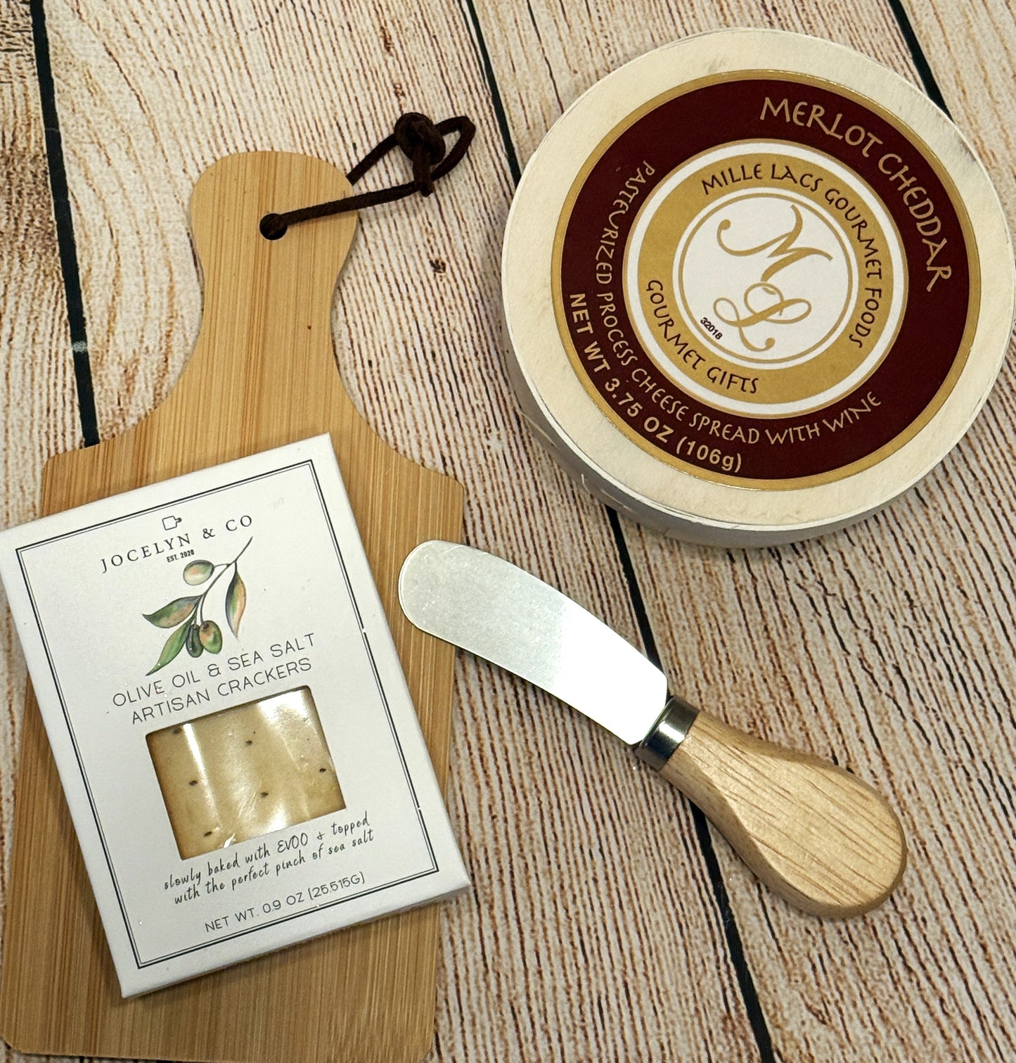 Cheese spread with wine, crackers, and a spreading tool on a wooden surface