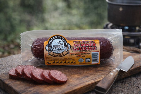 Packaged summer sausage with a label on a wooden cutting board outdoors.