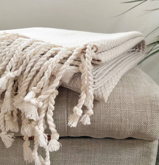 Beige blanket with tassels draped over a beige sofa Gift Basket Alaska