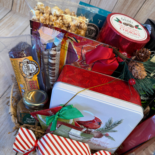 Gift basket with snacks, cookies, and a decorative tin on a wooden surface