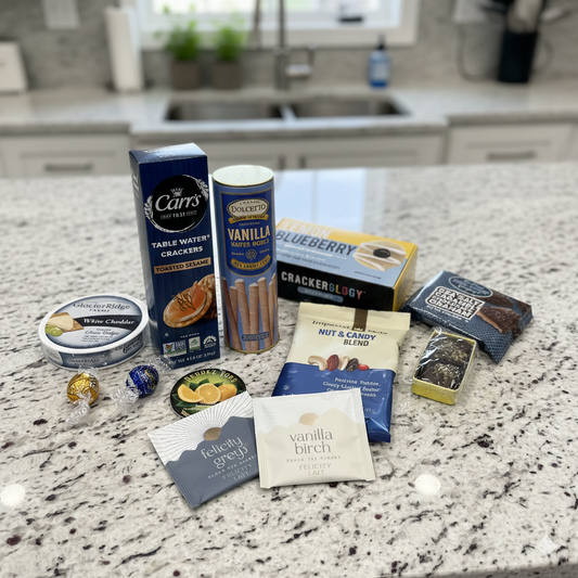 Afternoon Delights Gift Box featuring a selection of snacks including cheese spread, crackers, truffles, candies, nut blend, chocolate, and tea bags, elegantly arranged.