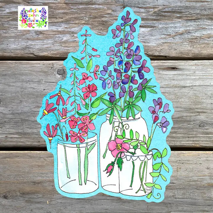 A sticker featuring a colorful illustration of flowers in jars against a blue background, placed on a wooden surface.