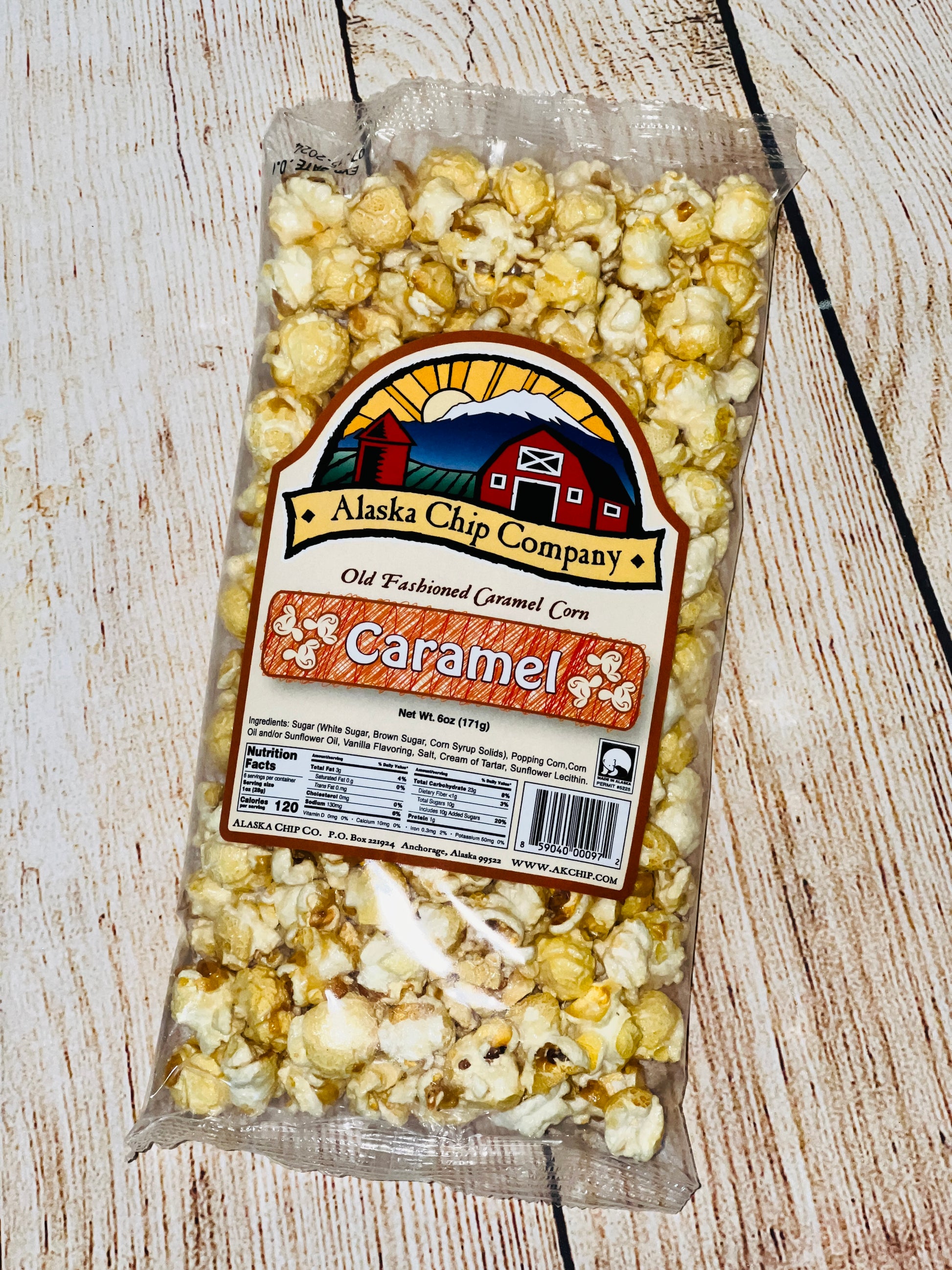 A bag of Alaska Chip Company Old Fashioned Caramel Corn popcorn on a wooden surface.