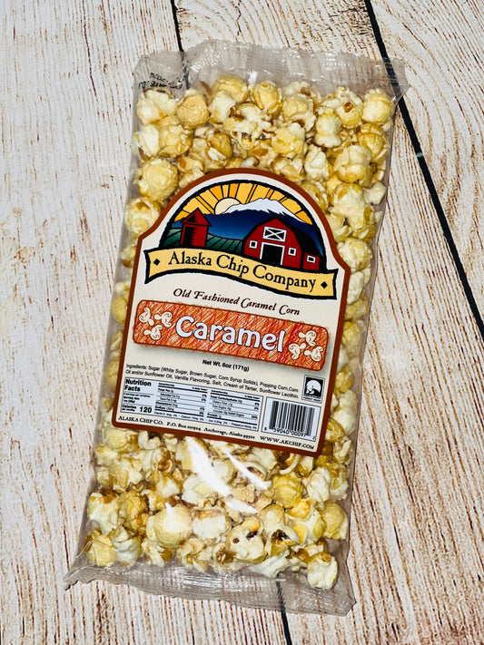 A bag of Alaska Chip Company Old Fashioned Caramel Corn popcorn on a wooden surface.