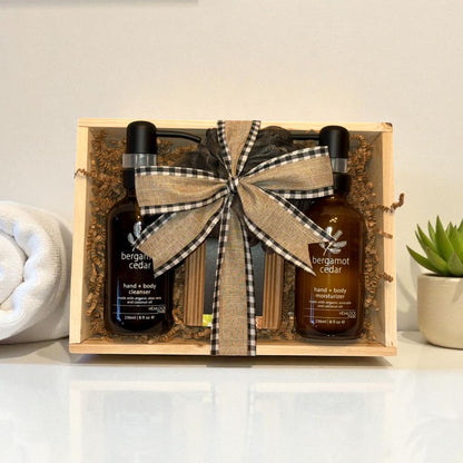 Gift set with two bottles of bergamot cedar product in a wooden crate with a bow, on a light background.