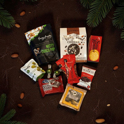 Assorted snack packages on a textured surface with greenery