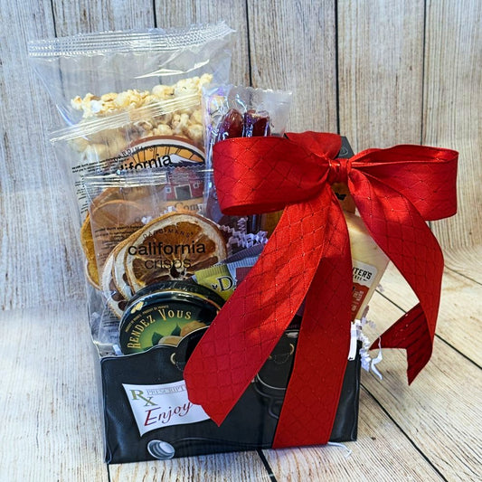A gift basket with a red bow containing dried fruits, caramel popcorn, crackers, cheese, meat sticks, hard candies, and tea bags.