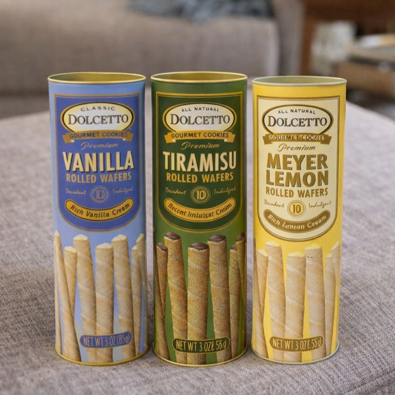 Three tubes of Dolcetto gourmet cookies with different flavors on a surface.