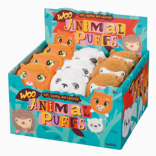 A box of Woo Animal Puffs stuffed toy balls in various cartoon animal designs, predominantly white and orange with textured surfaces.
