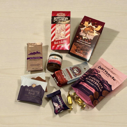 Assorted food items including chocolate bars, candies, and tea packages on a textured surface.