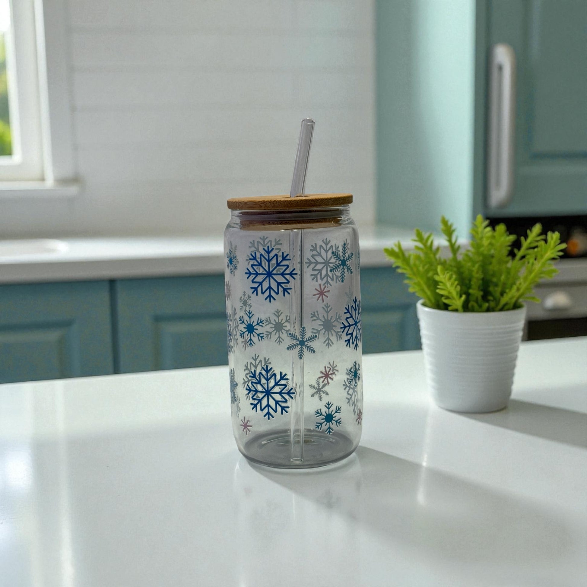 Glass Tumbler with snowflake motifs, bamboo lid, and glass straw on a countertop, exemplifying eco-friendly style for beverages.