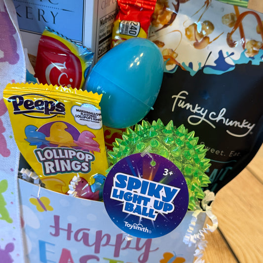 Happy Easter Gift Basket with Peeps Lollipop Rings, a blue egg, Toysmith light-up ball, Funky Chunky popcorn, and candies in a festive bag.