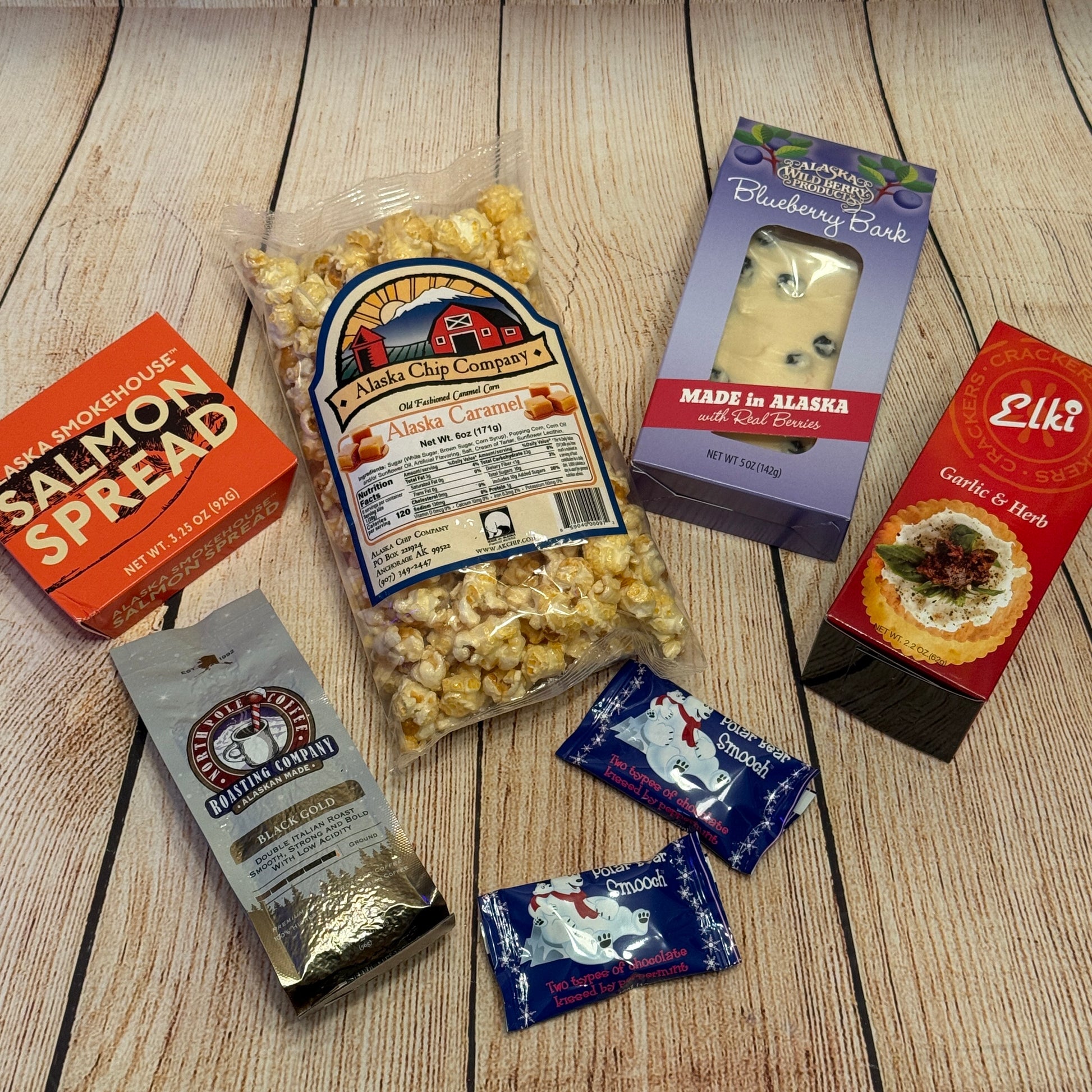 Assorted food products including popcorn, spreads, and cheese on a wooden surface