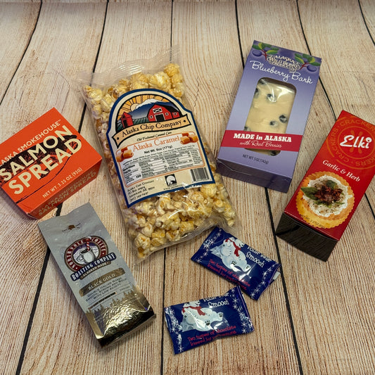 Assorted food products including popcorn, spreads, and cheese on a wooden surface