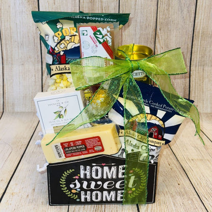 A gift basket with the text 'Home Sweet Home' containing various snack items including crackers, cheese, rolled wafers, meat stick, caramel popcorn, potato chips, and chocolate truffles.