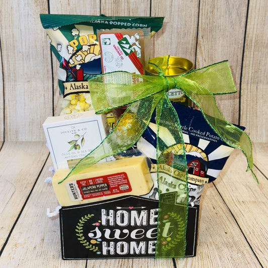 A gift basket with the text 'Home Sweet Home' containing various snack items including crackers, cheese, rolled wafers, meat stick, caramel popcorn, potato chips, and chocolate truffles.