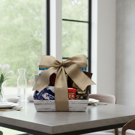 Last Frontier Alaska Gift Basket on table, featuring gourmet snacks like Wild Berry Bear Claws, smoked salmon, and North Pole Coffee, tied with burlap ribbon.