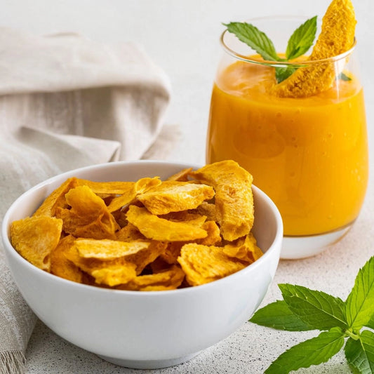 Bowl of yellow corn chips with a glass of orange juice on a light background