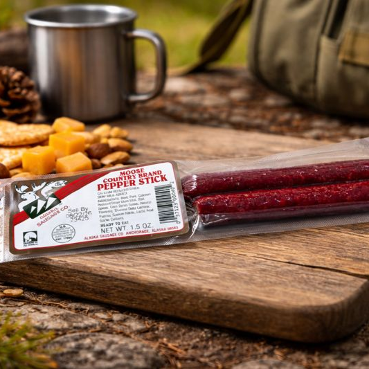 Packaged pepper sticks on a wooden cutting board with a mug and snacks in the background