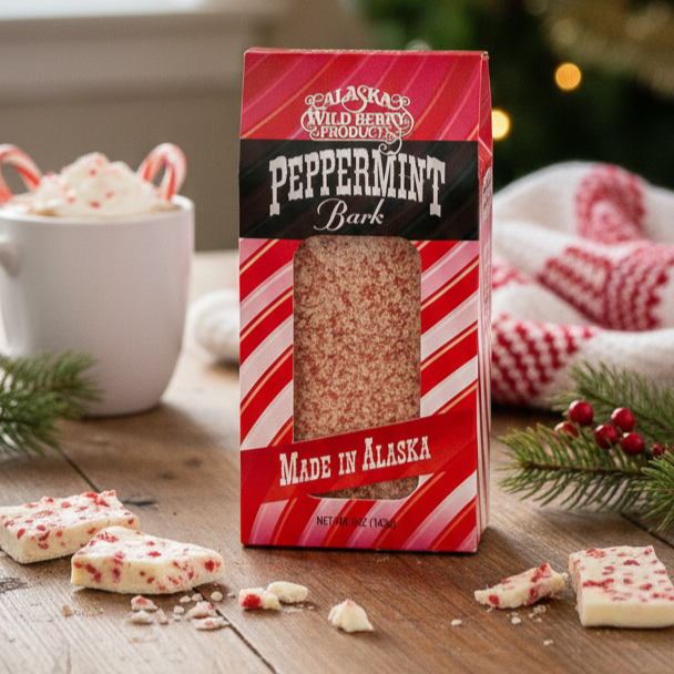 Peppermint Chocolate Bark: White chocolate bark with red peppermint bits, displayed with a festive setup featuring a mug with candy-canes and seasonal accents.