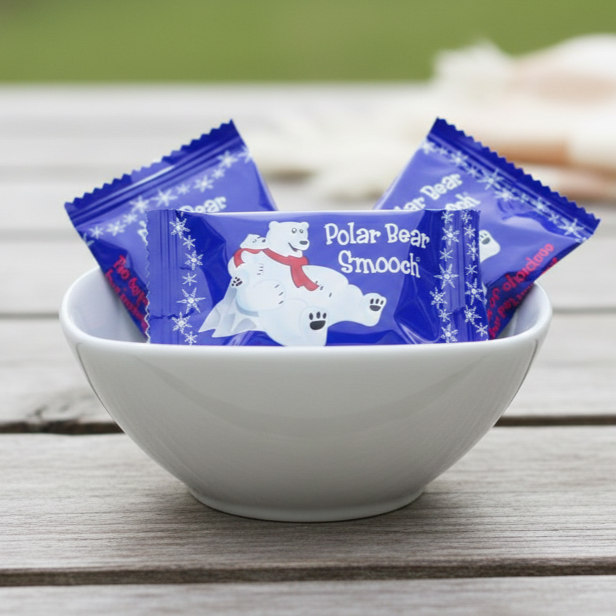 Bowl with 'Polar Bear Smooch' chocolate & peppermint candy packages on a wooden surface
