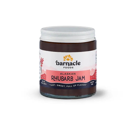 A jar of Barnacle Foods Alaskan Rhubarb Jam with a white label and red text, set against a plain background.