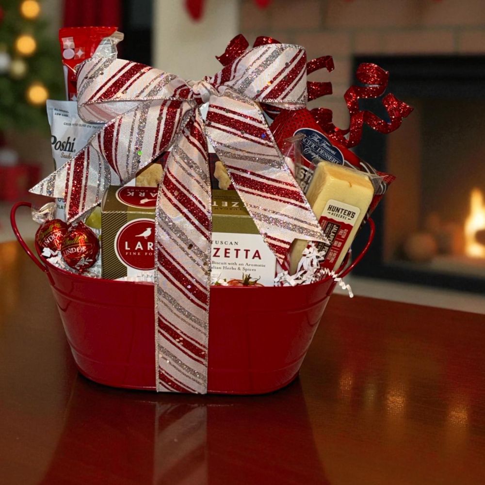 Gift basket with snacks and a bow in front of a fireplace