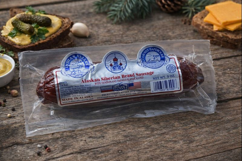 Alaskan Siberian Brand sausage package on a wooden surface with food items.