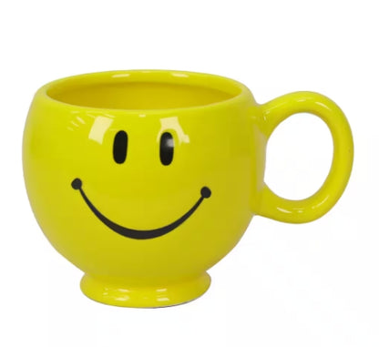 A yellow smiley face mug with a handle, suitable for holding coffee or tea.