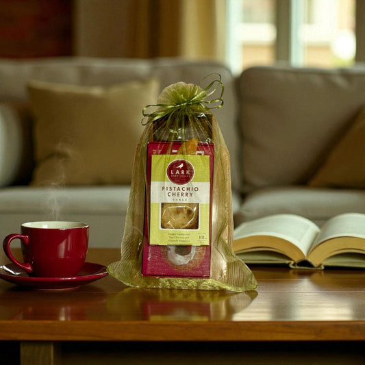 Packaged pistachio cherry treat on a table with a red mug and open book in a cozy living room setting.
