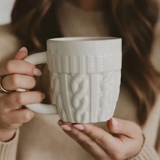 Person holding a textured white mug with a blurred background
