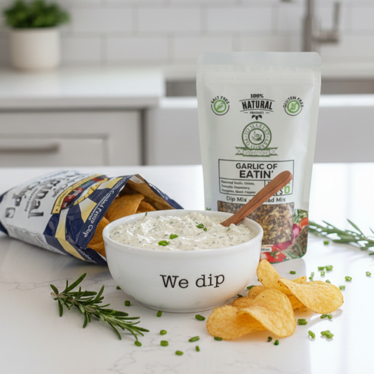 Garlic of Eatin' dip mix with a bowl of dip and chips on a kitchen counter.