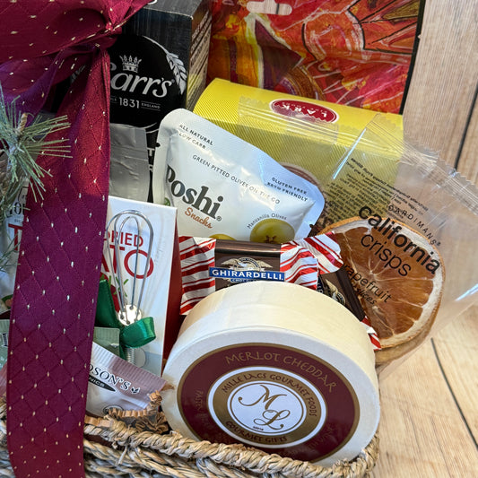 Gift basket with cheddar cheese, crackers, and other snacks on a wooden surface