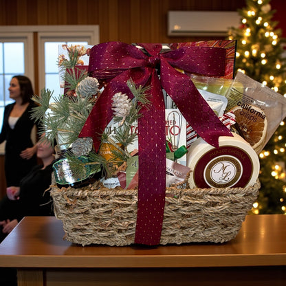 Gift basket with a red ribbon on a table in front of a Christmas tree.