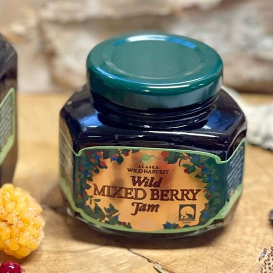 Jar of Wild Mixed Berry Jam with a green lid on a wooden surface