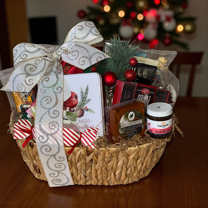 Gift basket with decorative bow on a wooden table in front of a Christmas tree.